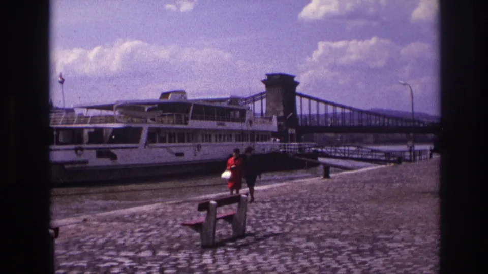 The final 1967 France frame shows the women near a foreground bench, with the docked riverboat and suspension bridge across the water.