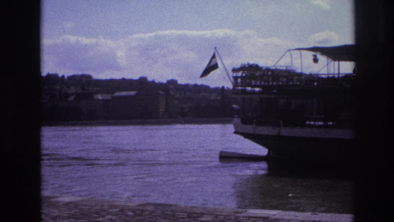 1967 France 8mm frame showing part of a docked riverboat, a small flag, calm water, and distant shoreline through dark framing.