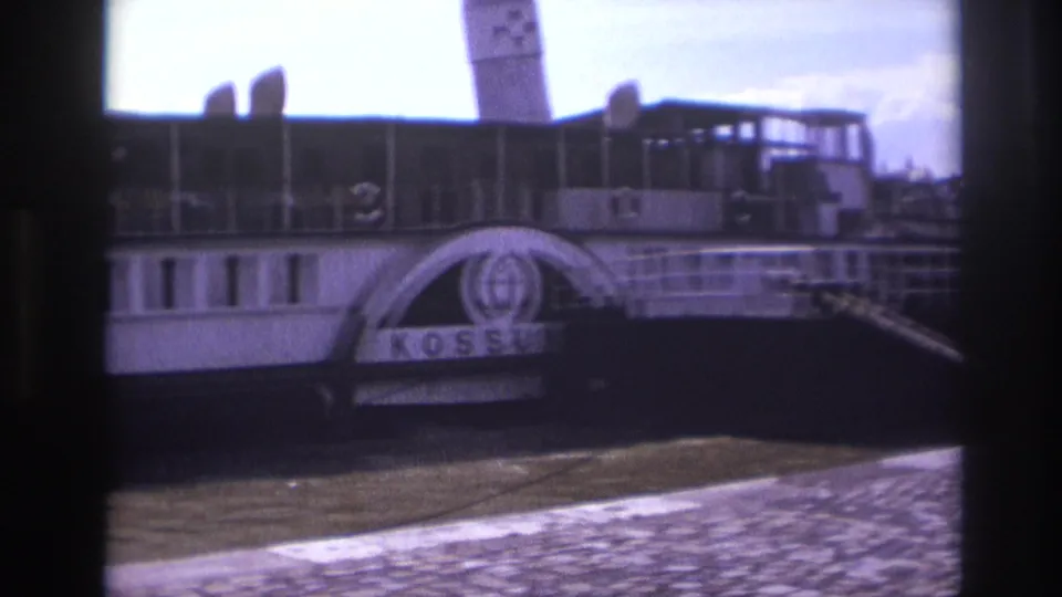 The docked paddlewheel boat shows the name Kossuth and an anchor emblem beside the cobblestone riverside in France, 1967.