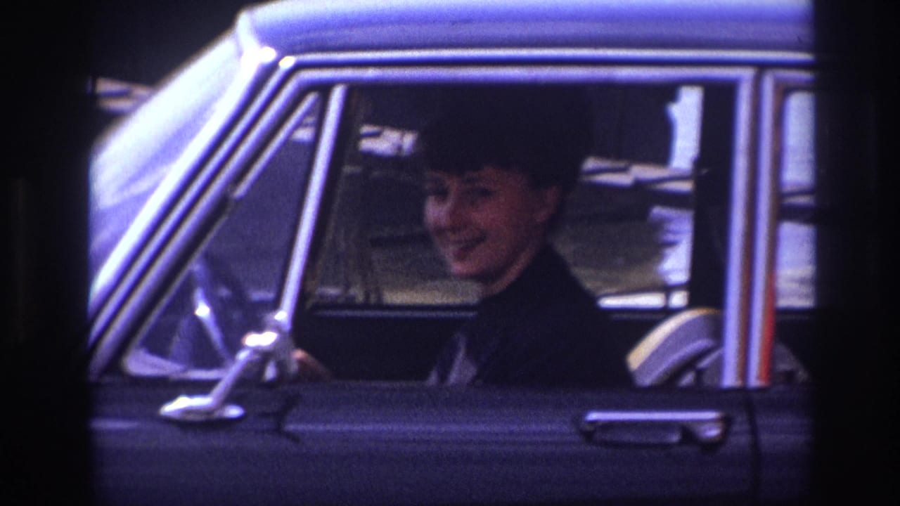 Closer view of a woman smiling inside a black car.