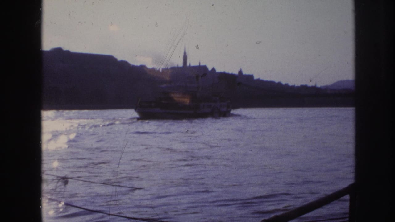 1967 France 8mm view of a ferry on a river, with a distant city skyline, church spire, and dark frame edges.
