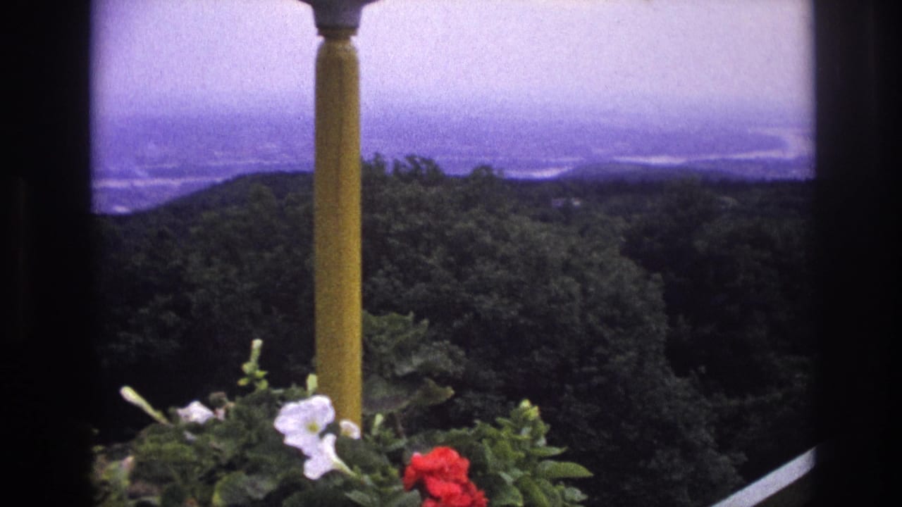 1967 France 8mm frame showing a yellow balcony column, flower boxes, trees, and hazy distant water.