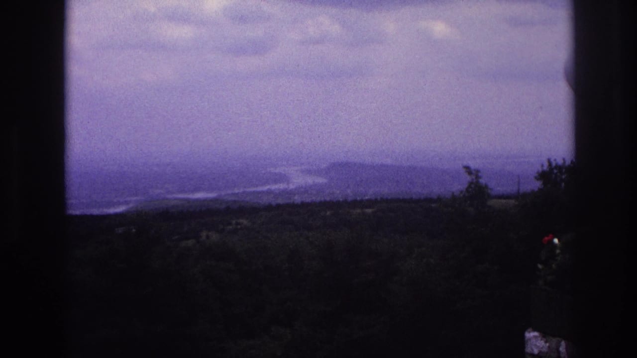 Hazy river and hills under clouds, viewed through dark vertical framing.