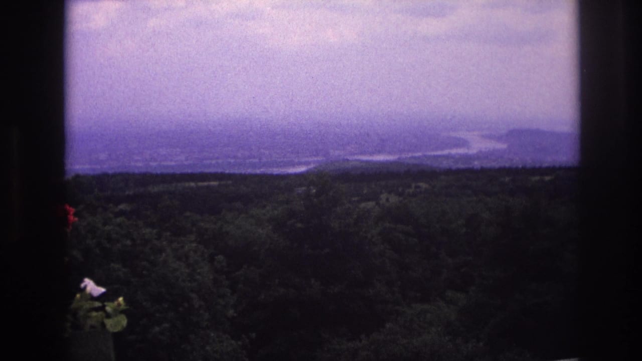 1967 France 8mm frame showing a distant broad river and forested landscape, partially framed by dark edges.