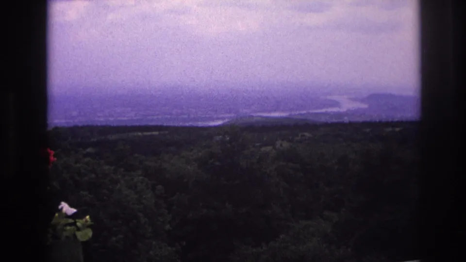 1967 France 8mm frame showing a distant broad river and forested landscape, partially framed by dark edges.