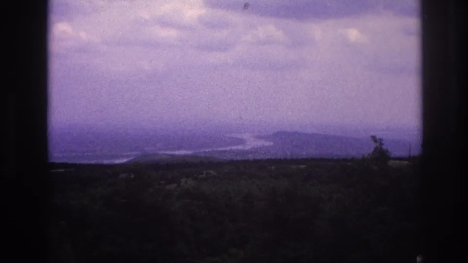 1967 France scenic overlook with a pale winding river, forested foreground, and dark vertical window-like borders.