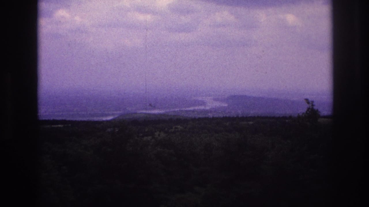 1967 France 8mm frame showing a distant mountain landscape and waterway through a dark window frame.