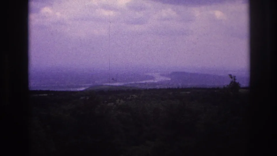1967 France 8mm frame showing a distant mountain landscape and waterway through a dark window frame.