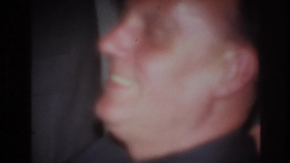 A very soft close-up from the 1967 France 8mm footage frames the man's smiling face during the celebration.