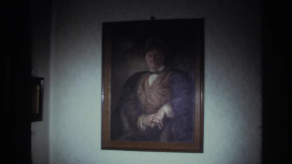 1967 France 8mm frame showing a framed oil portrait of a formally dressed man on a wall inside a low-lit private interior.