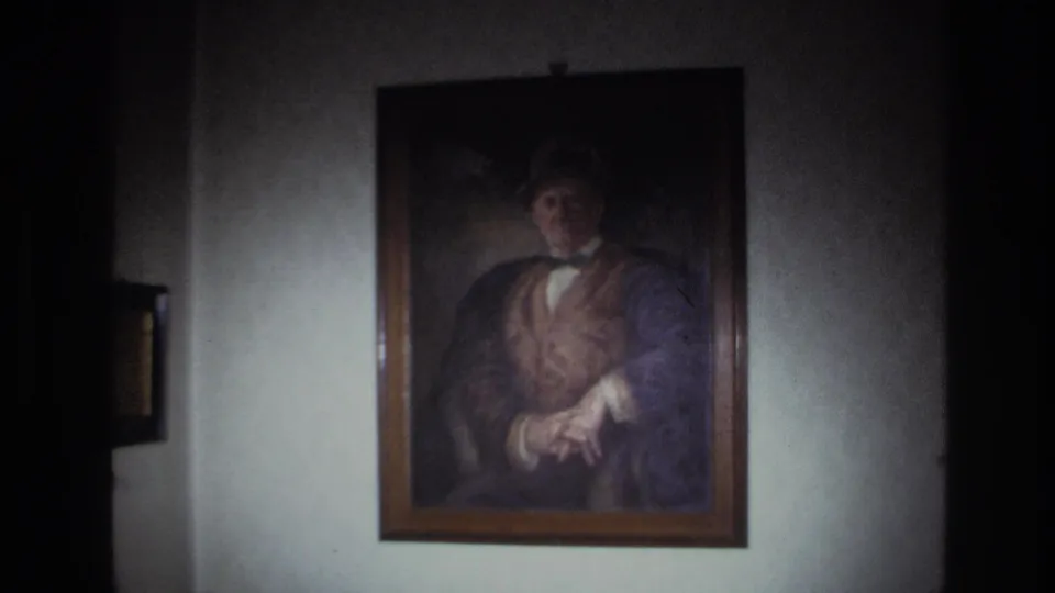 The camera lingers on a framed oil portrait in a dim French interior from 1967, with soft 8mm grain and uneven light on the wall.