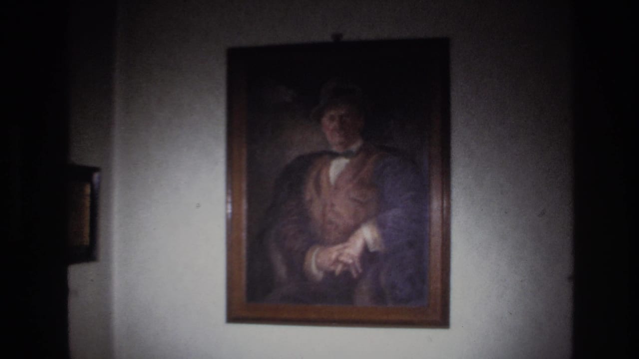 Framed portrait on a wall, centered between dark vertical shadows.