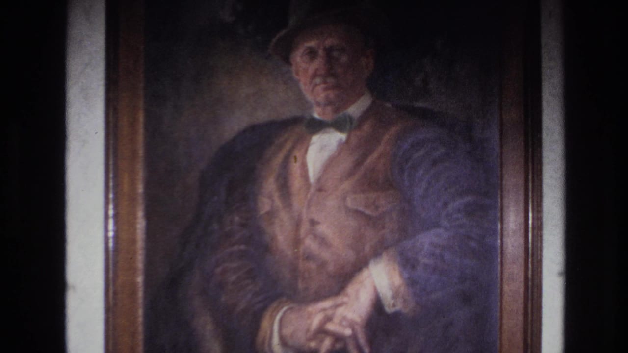 Framed portrait of an older man, still close but with more of the frame visible.