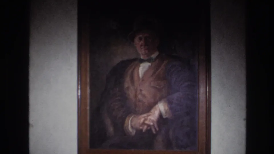 1967 France 8mm frame showing the framed painted portrait on a plain wall, with dark interior edges around the shot.