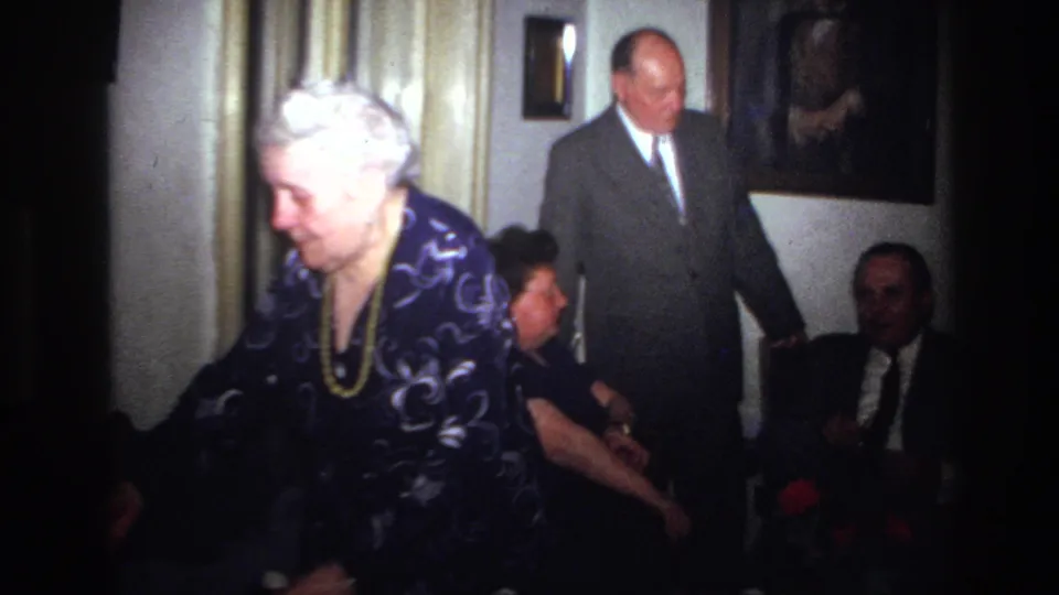 1967 France frame of an elderly woman turning away from relatives seated in a dim private interior.