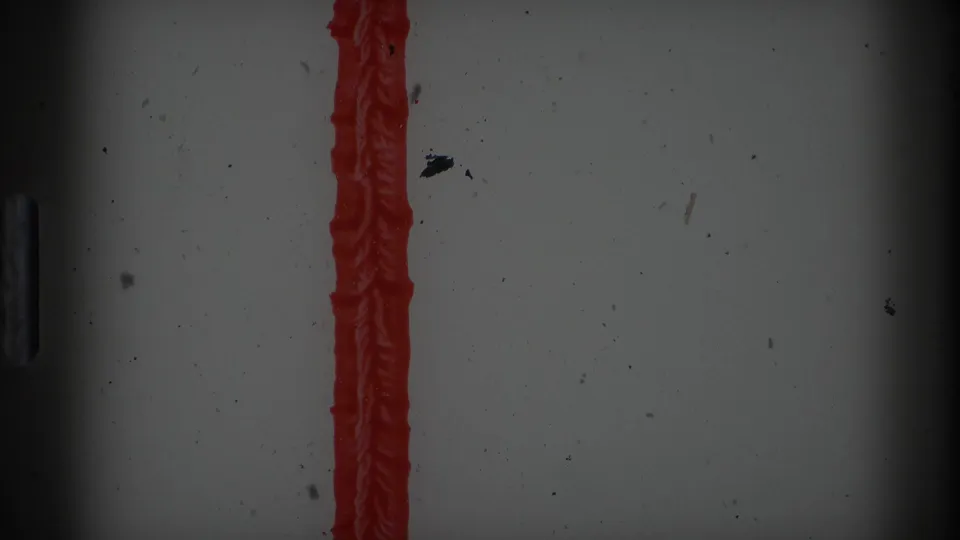 8mm film edge or leader area with a vertical red stripe, dark vignette, dust, and surface marks from the scan.