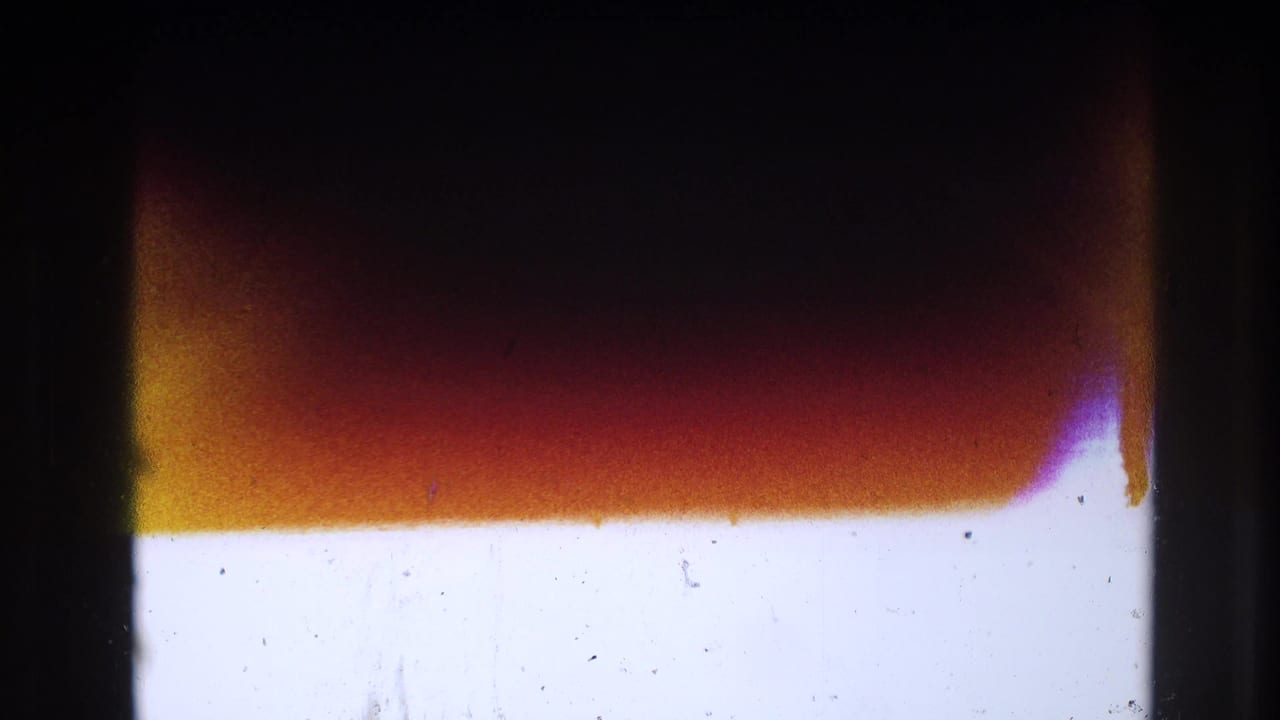 Abstract 8mm frame area showing overexposure, dark gate borders, warm red-orange banding, dust, and scratches.