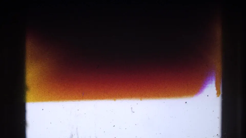 Abstract 8mm frame area showing overexposure, dark gate borders, warm red-orange banding, dust, and scratches.