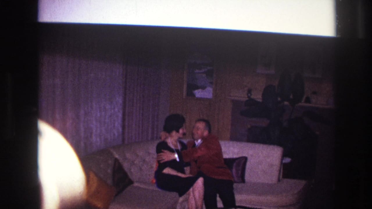 Seated couple embraces and kisses on a couch.