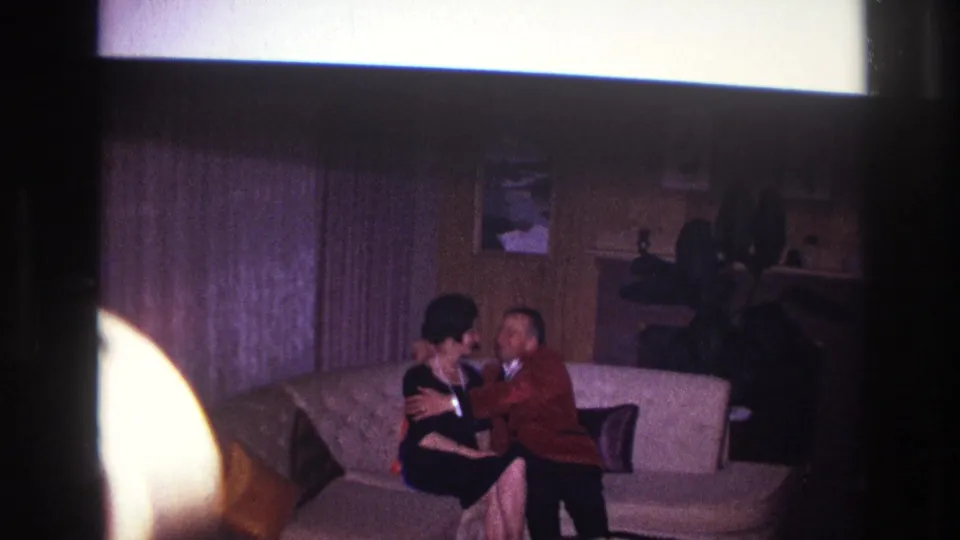 The man leans toward the woman and kisses her as they sit together on the couch in the Ottawa living room.