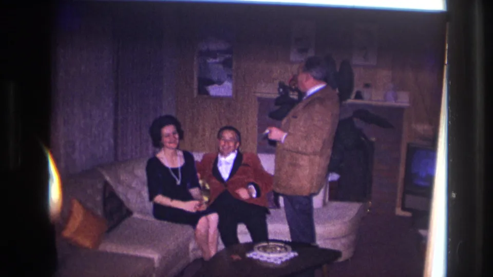 1967 Ottawa home-movie frame of three adults laughing and holding drinks in a private living room.