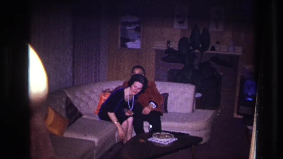The woman leans toward the coffee table while the man remains seated beside her in the Ottawa living room scene.