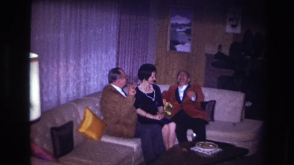 In the final Ottawa frame, the three adults appear animated and cheerful on the sofa, surrounded by curtains, pillows, wall art, and a coffee table.