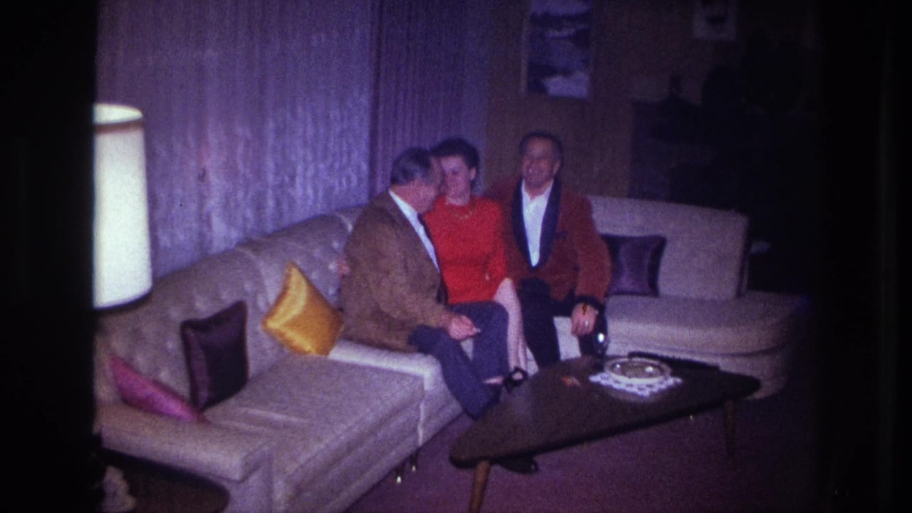 Three adults appear to smile or pose on a sectional couch in an Ottawa living room filmed on 8mm in 1967.