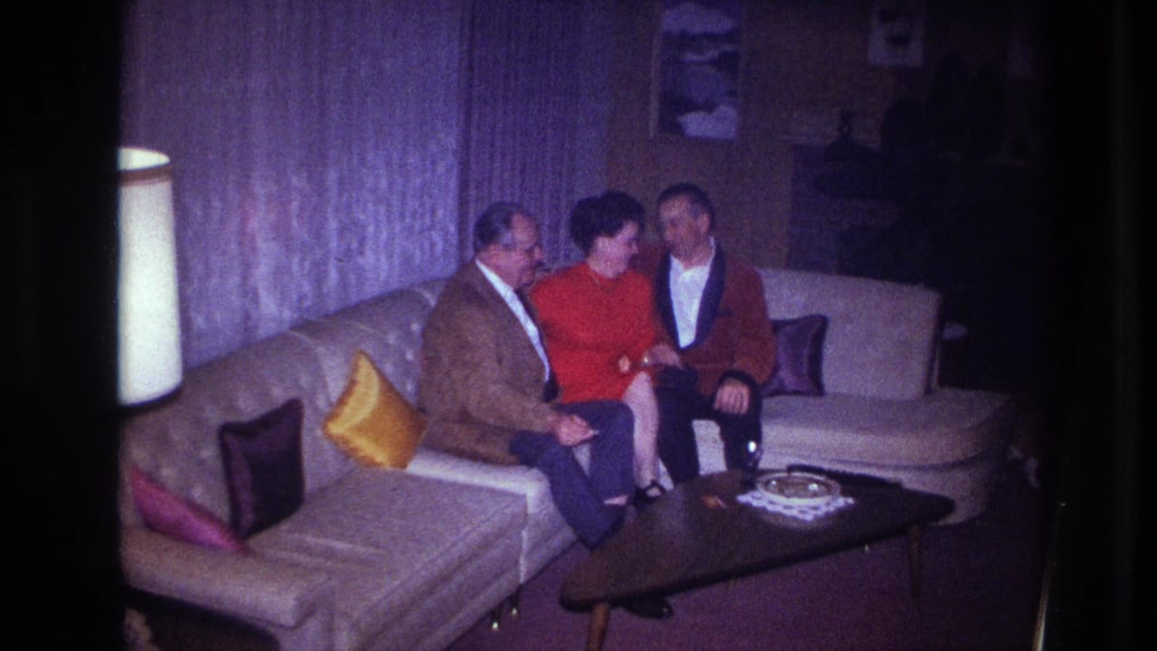 The woman in red turns toward one man while the other remains close beside her in the Ottawa home interior.