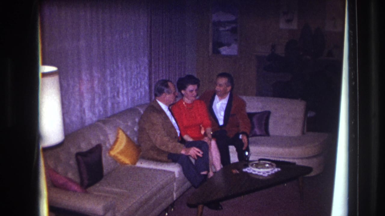 Two men and a woman seated together on a couch near a coffee table.