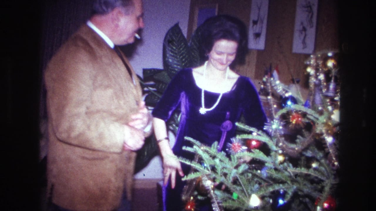 In 1967 Ottawa home-movie footage, a couple stands near a small Christmas tree with ornaments, tinsel, and lights.