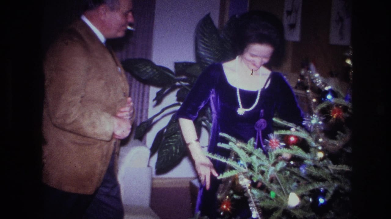 The woman reaches into the decorated tree as the man watches in this 1967 Ottawa holiday home-movie frame.