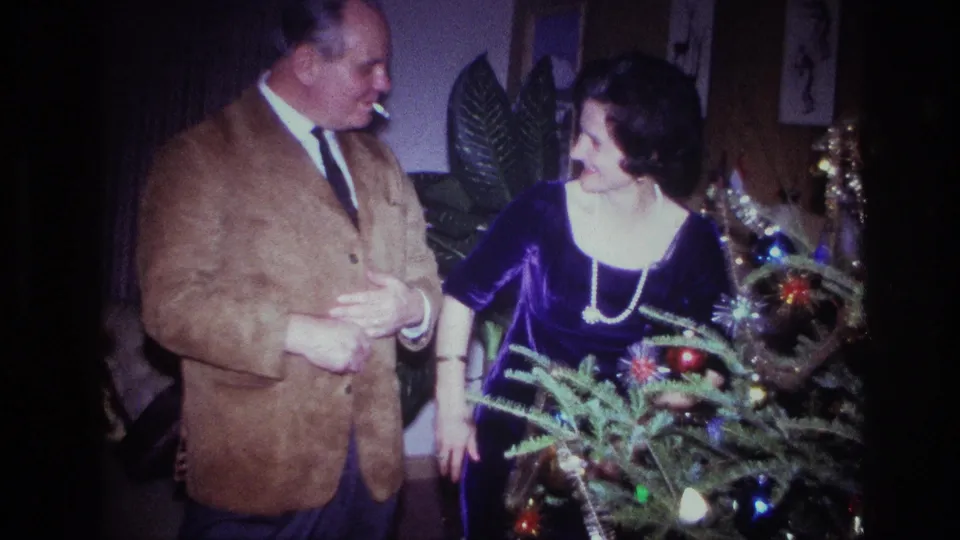 The couple shares a smiling moment beside the decorated tree in a 1967 Ottawa private living room.