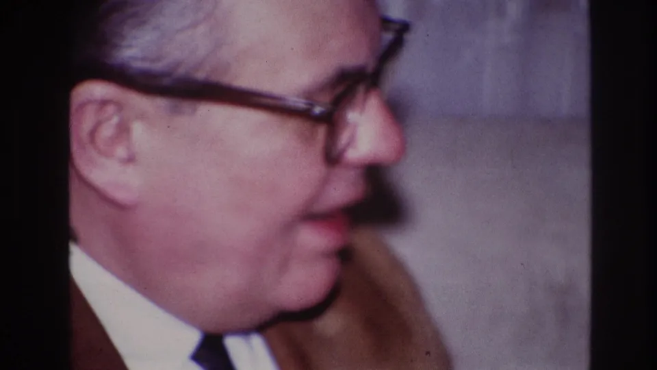 Close profile of a gray-haired man in glasses and a brown jacket, filmed indoors in Ottawa home-movie footage from 1967.
