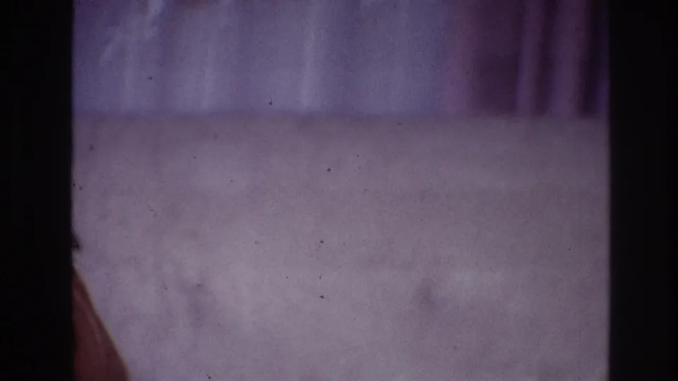 1967 Ottawa home-movie frame showing purple carpet, draped curtain, film borders, and a partial arm near the left edge.
