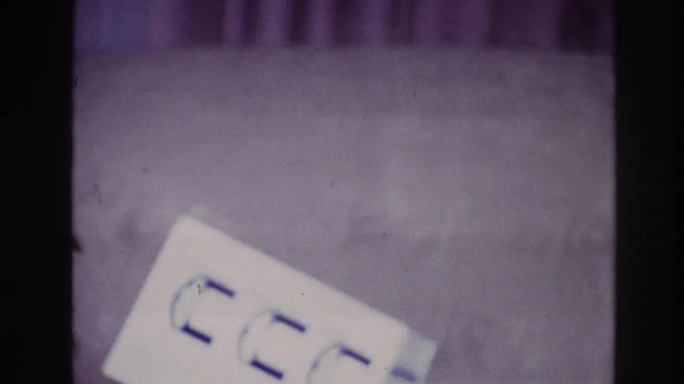 1967 Ottawa close-up showing a white paper with blue markings against a purple carpet in grainy 8mm home-movie footage.
