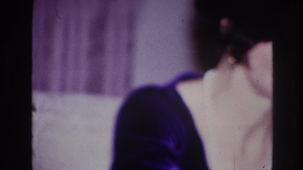 1967 Ottawa home-movie frame showing a woman turning in profile in a softly focused private living room setting.