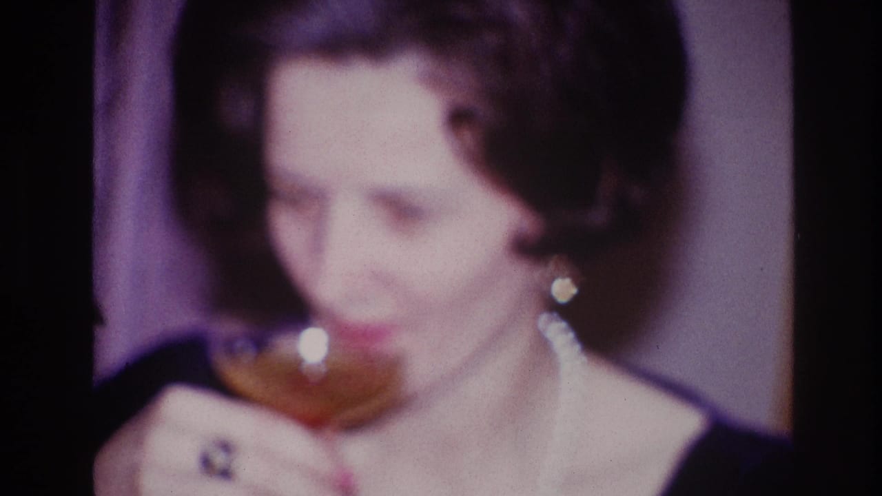 In the Ottawa 1967 home-movie frame, the woman raises a stemmed drink glass, with her ring and earrings catching light.