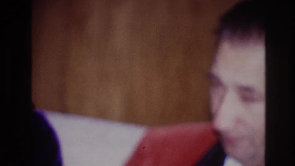 A man appears at the right edge of the 1967 Ottawa home-movie frame, wearing dark clothing near a private interior wall.