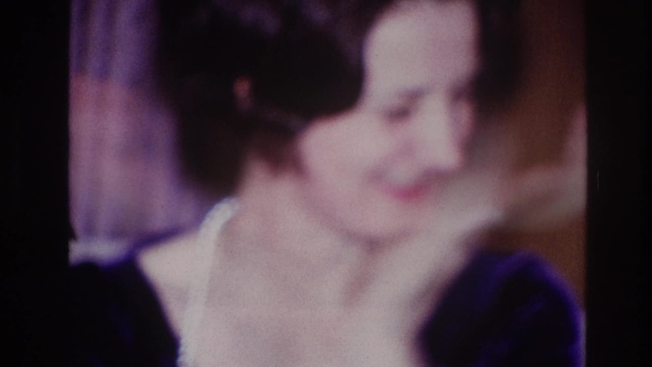 Adult woman in a dark dress smiles in soft focus indoors.