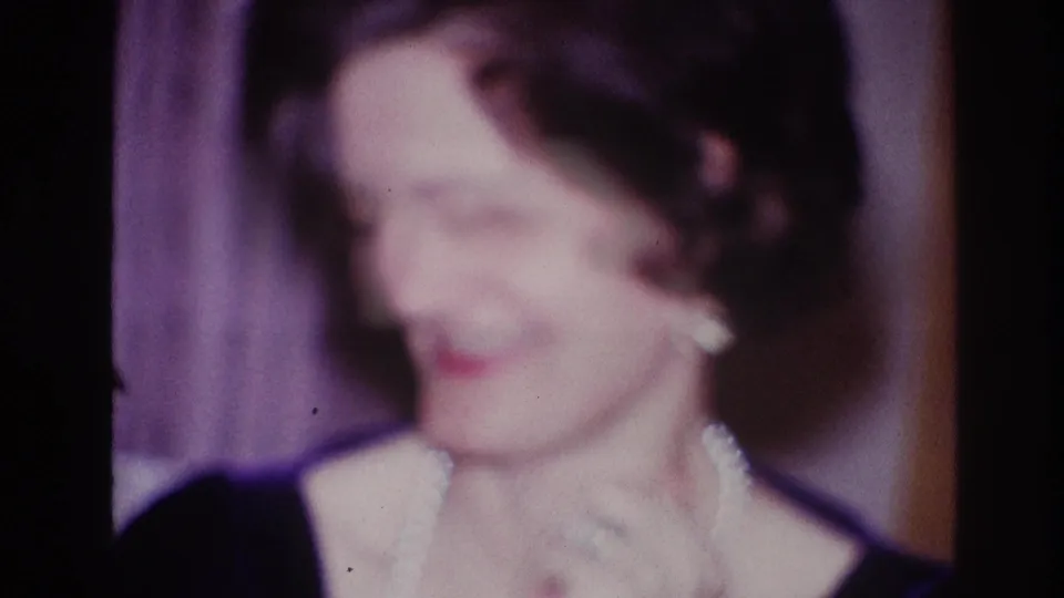 In Ottawa 1967 home-movie footage, a woman in formal dress and pearls appears on stage in soft focus.