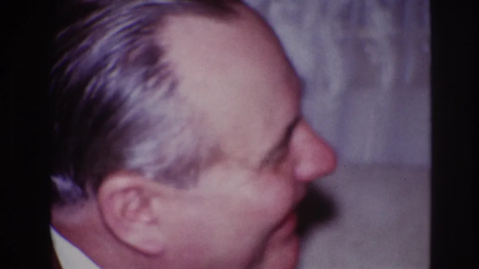 A close 1967 Ottawa frame shows an older man in right-facing profile, softly focused against a light interior background.