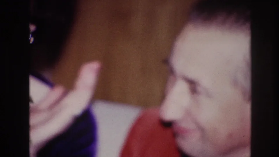 1967 Ottawa home-movie frame with the man in profile beside the woman’s raised hand in a softly lit interior.