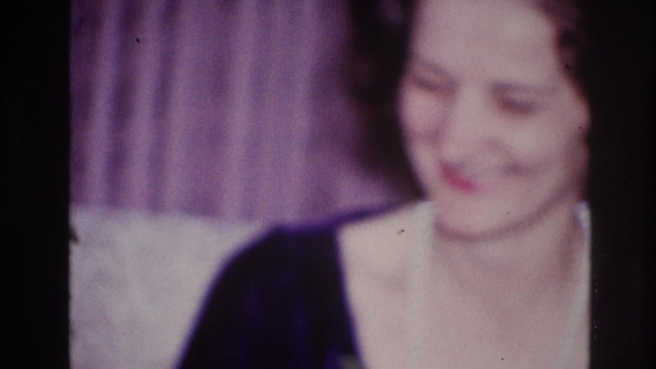 Woman in dark dress and pearls smiling toward the camera.