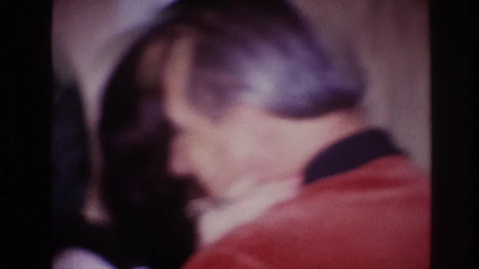 A man in a red jacket holds a woman close during an affectionate moment in 1967 Ottawa footage.