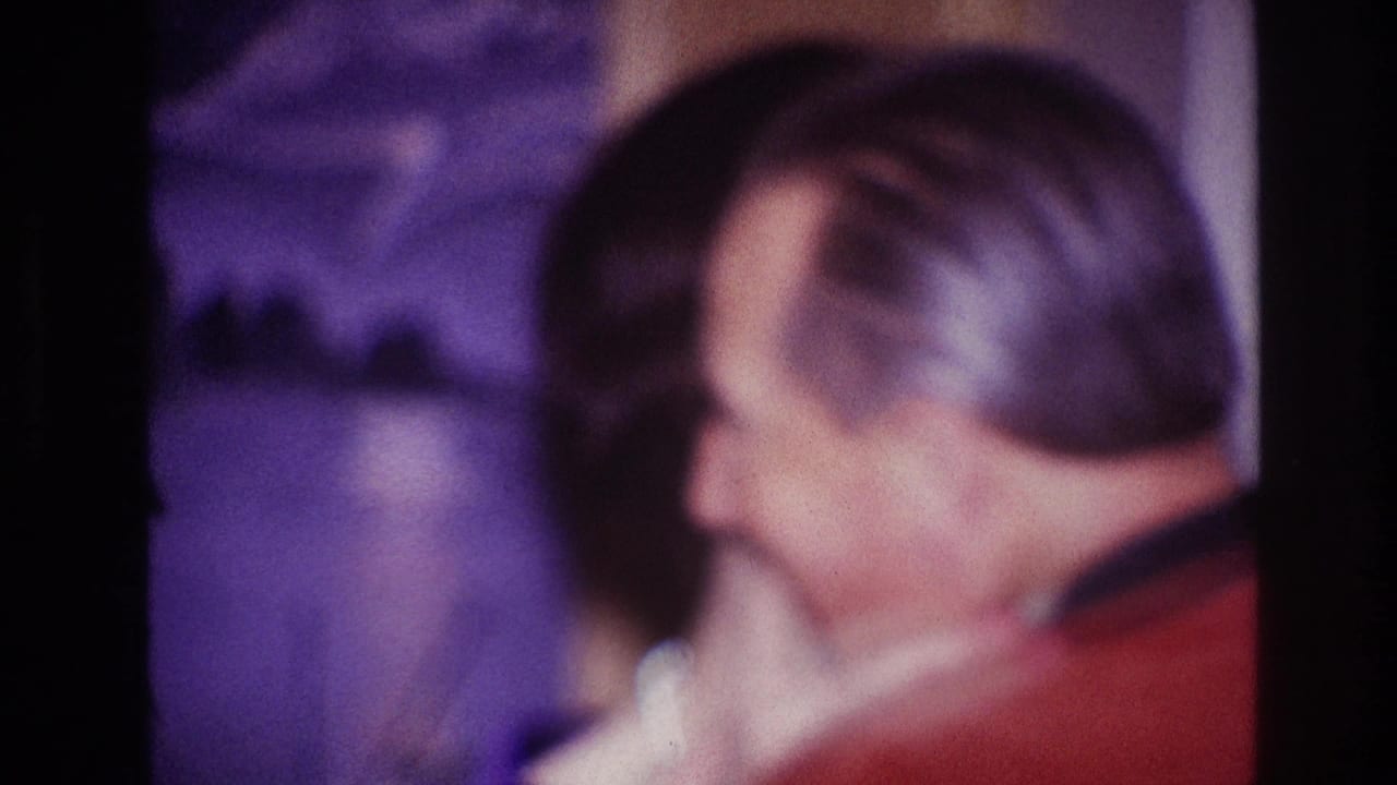 Woman in profile dances cheek to cheek with a man in a red jacket.