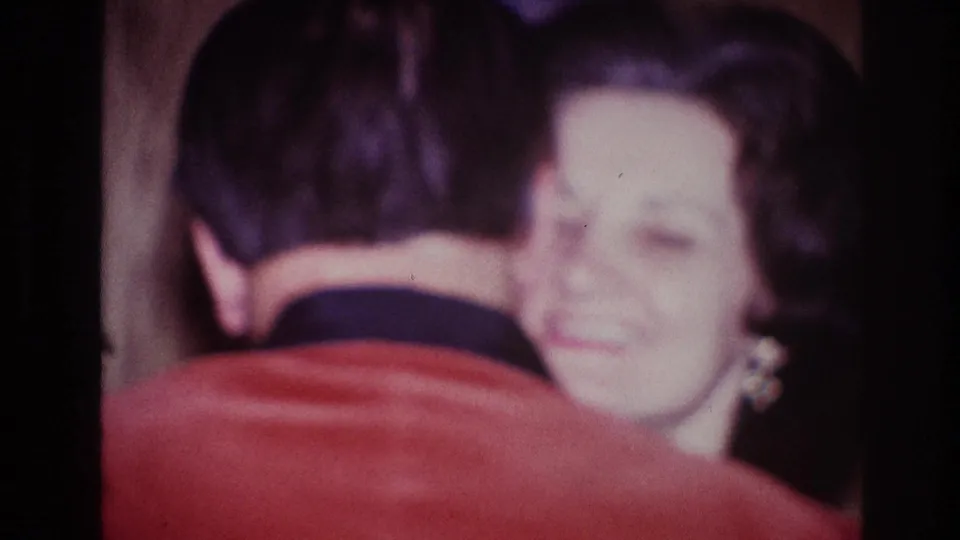 The woman smiles softly toward the camera as she dances closely with the man in this 1967 Ottawa home-movie frame.