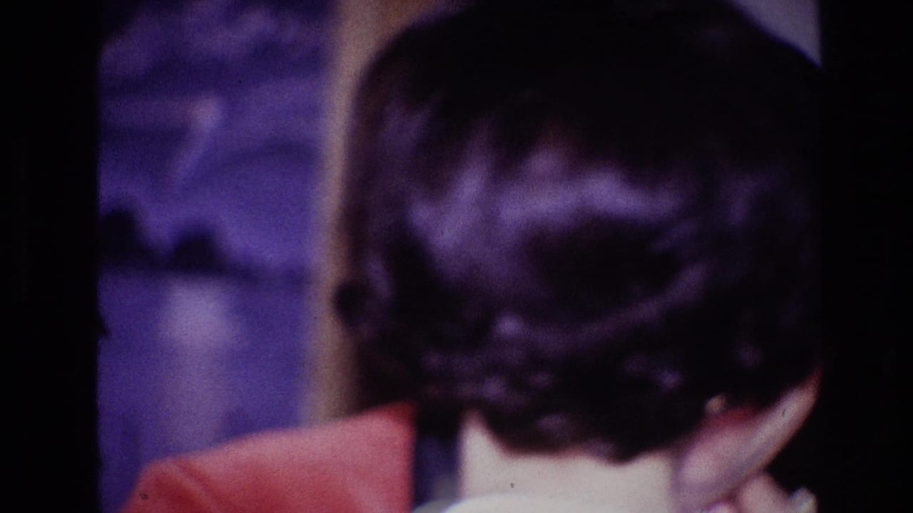 Older woman seen from behind near an older man during a formal indoor gathering.
