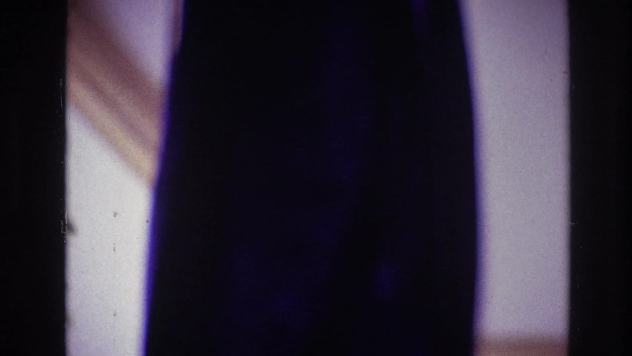 Partial indoor view of a woman and dark vertical film-frame division.