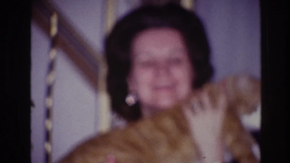 Woman in a dark top faces the camera while holding a ginger-and-white cat in 1967 Ottawa home-movie footage.